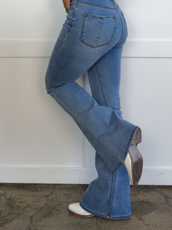 Person wearing blue flared jeans with a white background