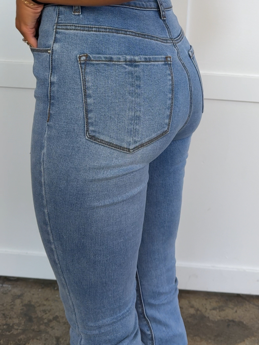 Blue jeans worn by a person against a white wall.