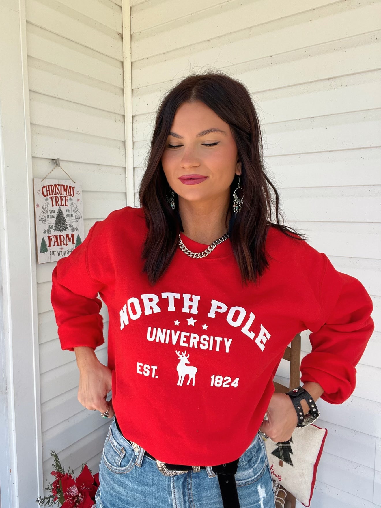 Person wearing a red 'North Pole University' sweatshirt in a festive setting.