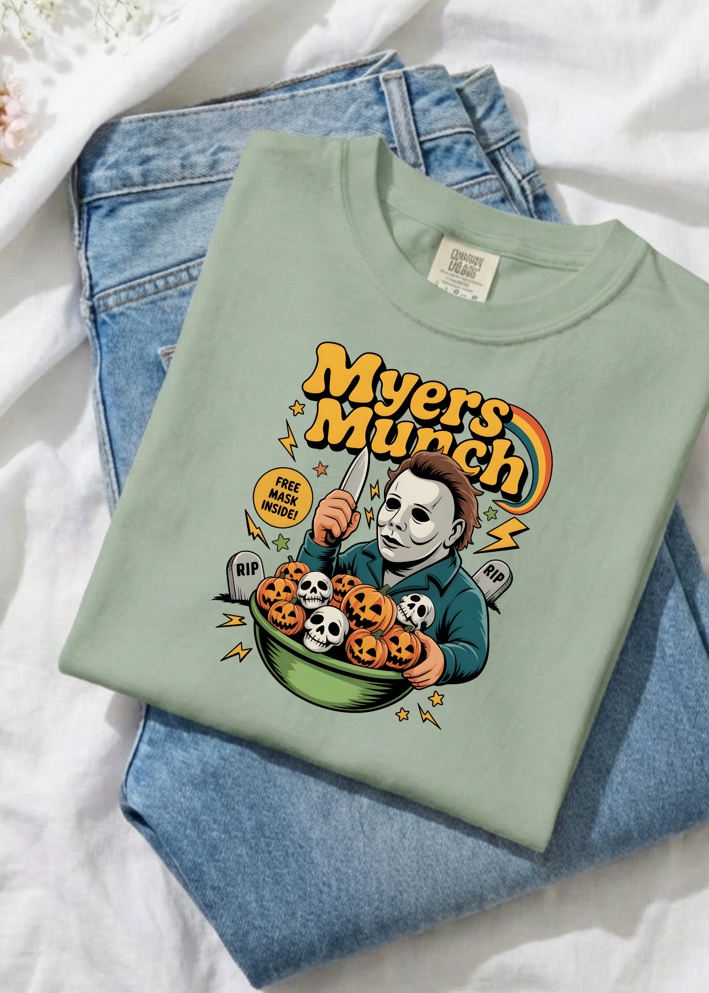 Light green t-shirt with 'Myers Munch' graphic design on a white surface with jeans.