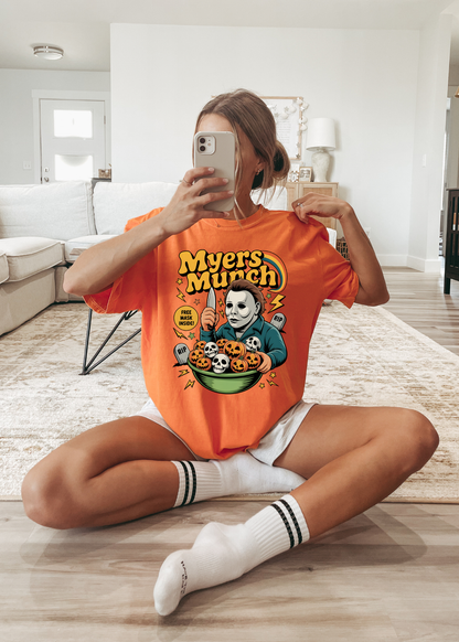 Person wearing an orange 'Myers Munch' t-shirt in a living room.