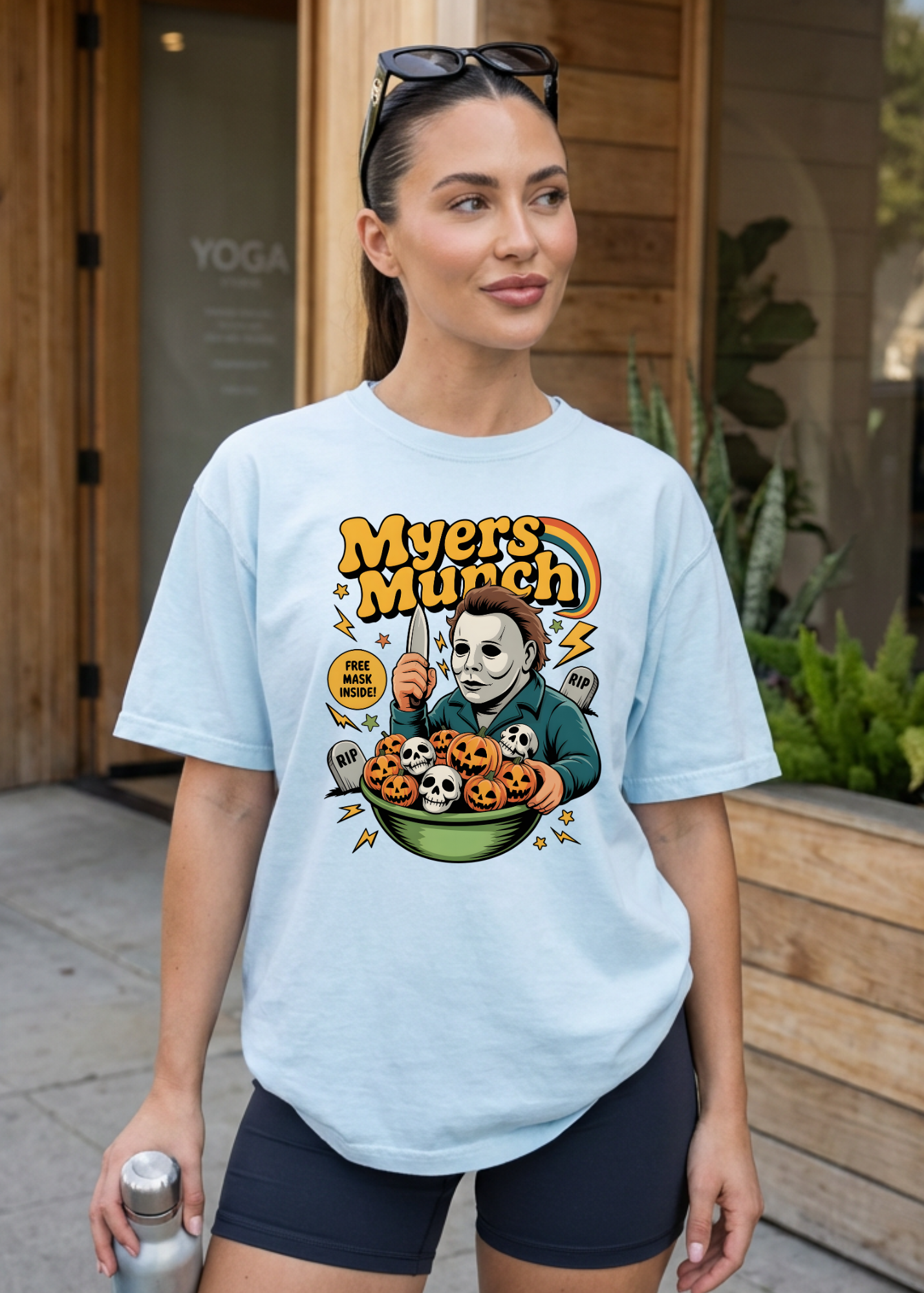 Woman wearing a light blue t-shirt with a graphic design, standing outdoors.