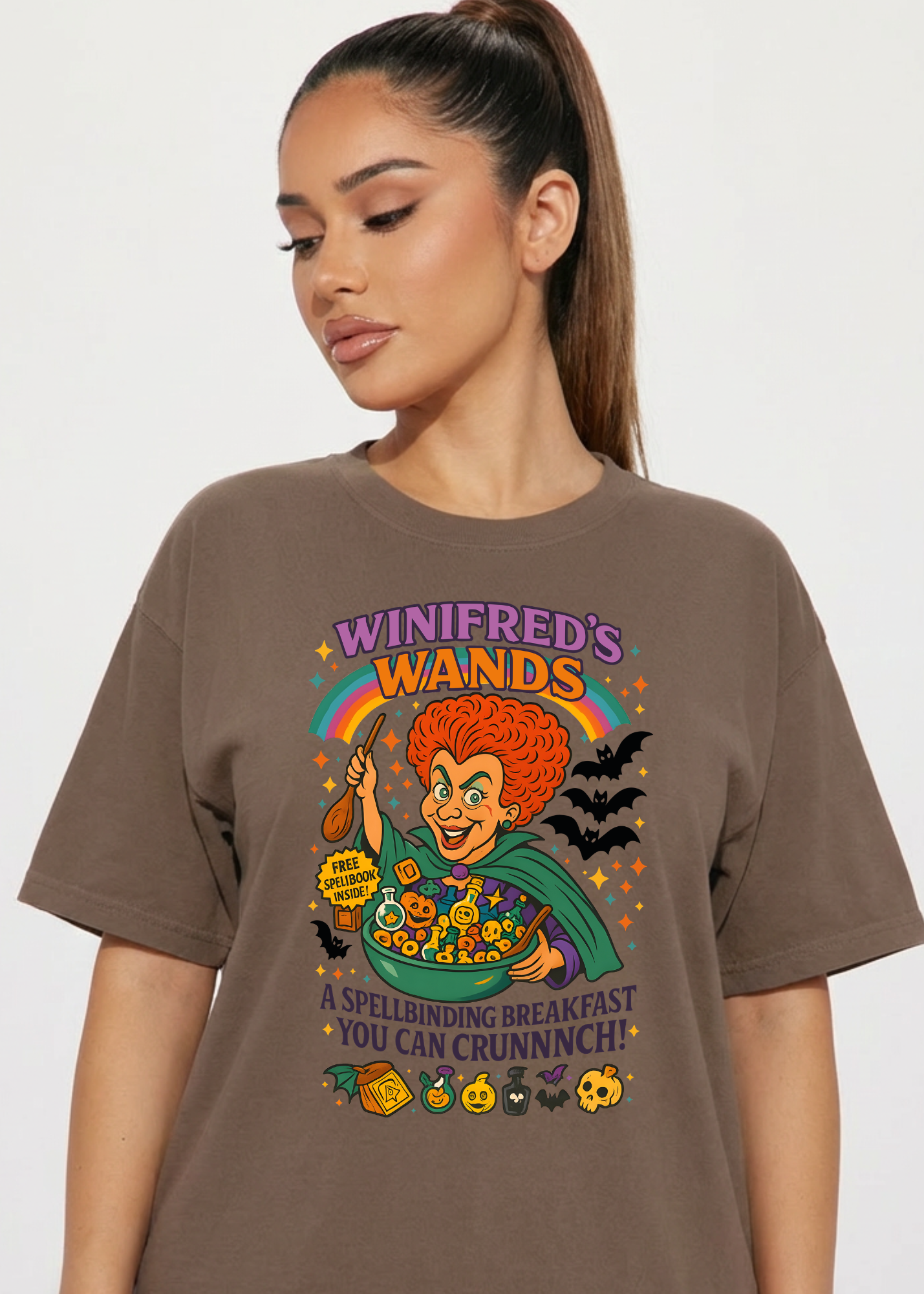 Woman wearing a brown t-shirt with a colorful graphic design on a plain background