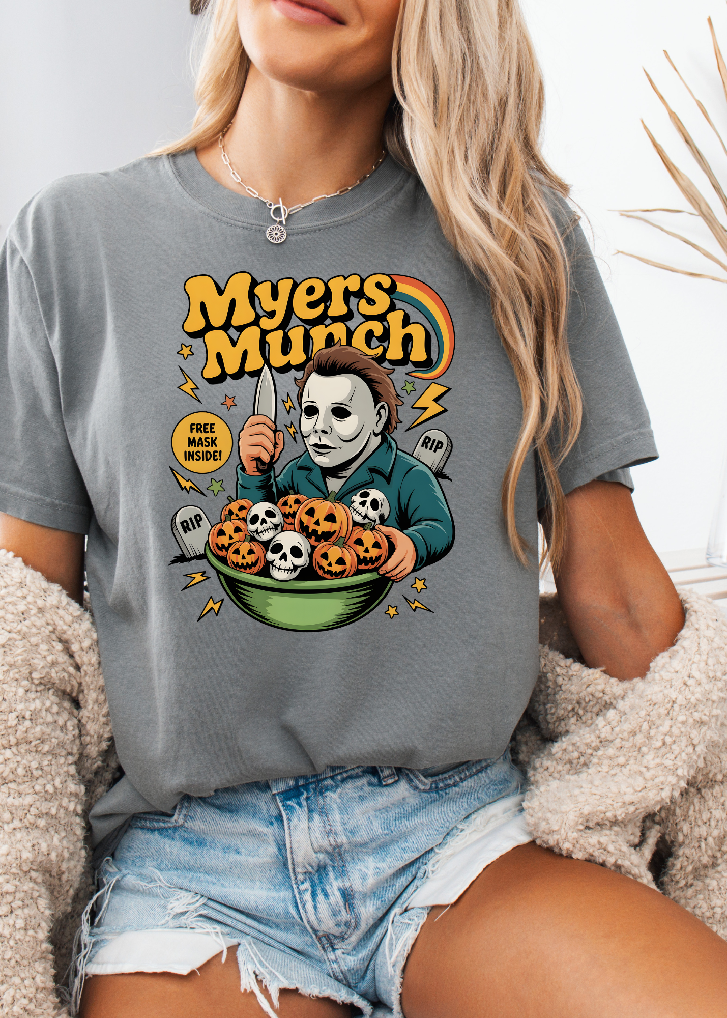 Person wearing a t-shirt with a graphic design of a character holding pumpkins and text 'Myers Munch'.