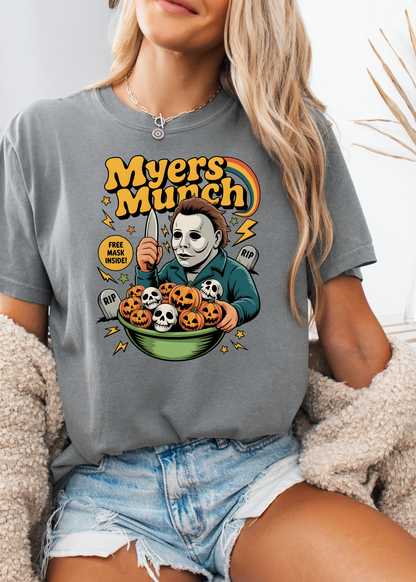 Person wearing a t-shirt with a graphic design of a character holding pumpkins and text 'Myers Munch'.