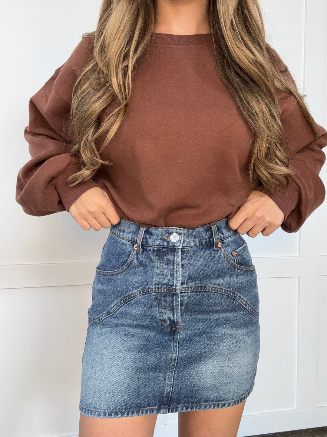 Person wearing a brown shirt and denim shorts against a white background