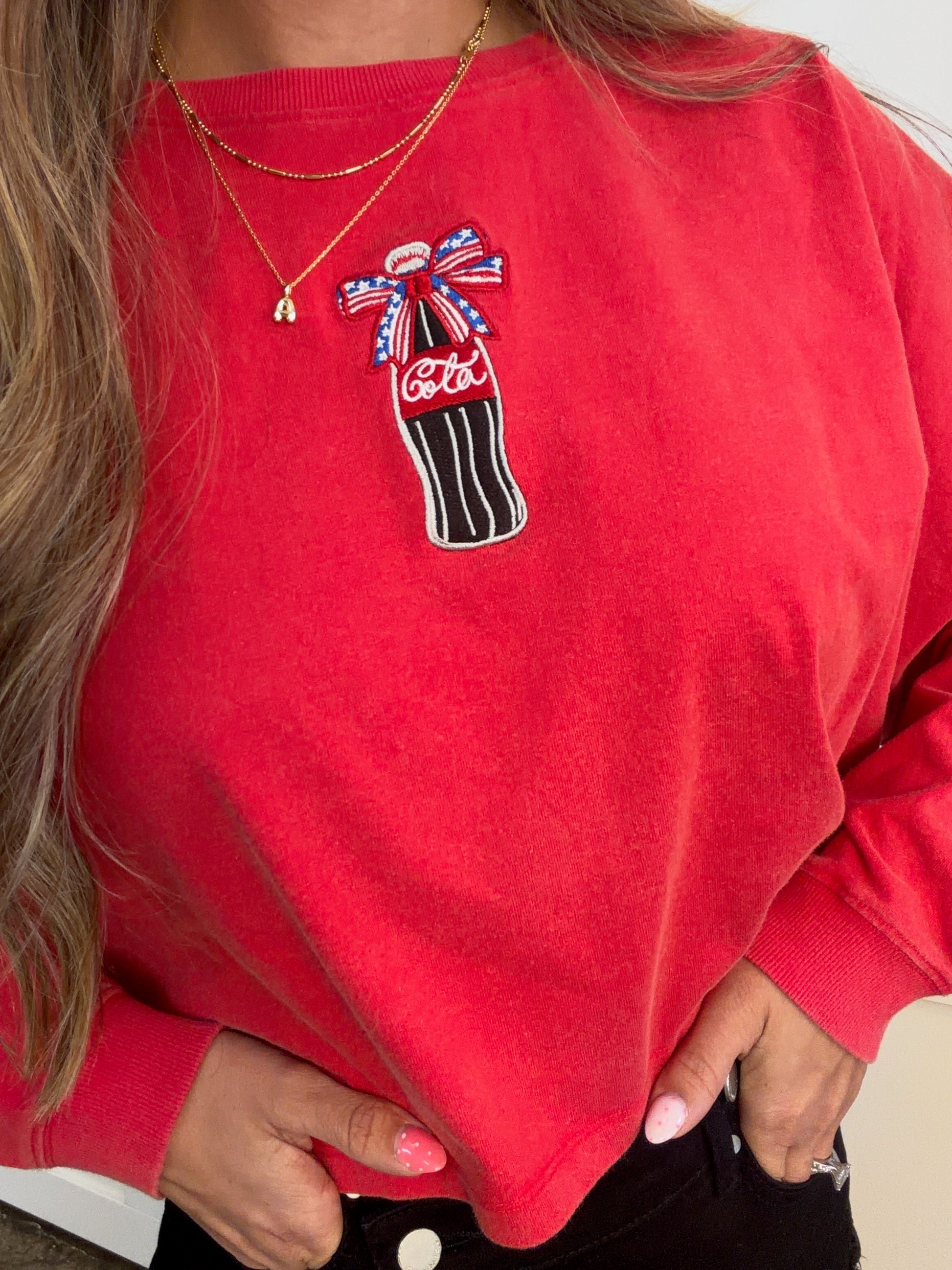 Red sweatshirt with Coca-Cola bottle graphic and bow design.