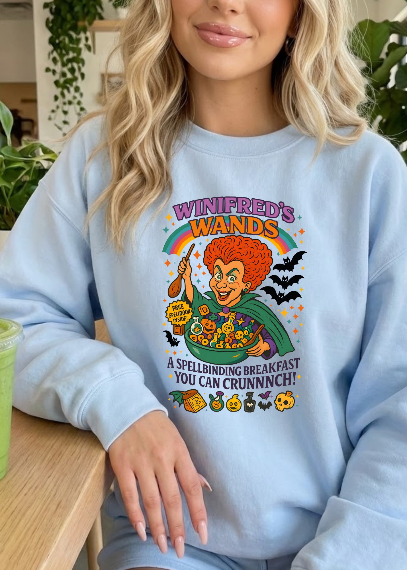 Person wearing a light blue sweatshirt with a colorful graphic design, sitting at a table.