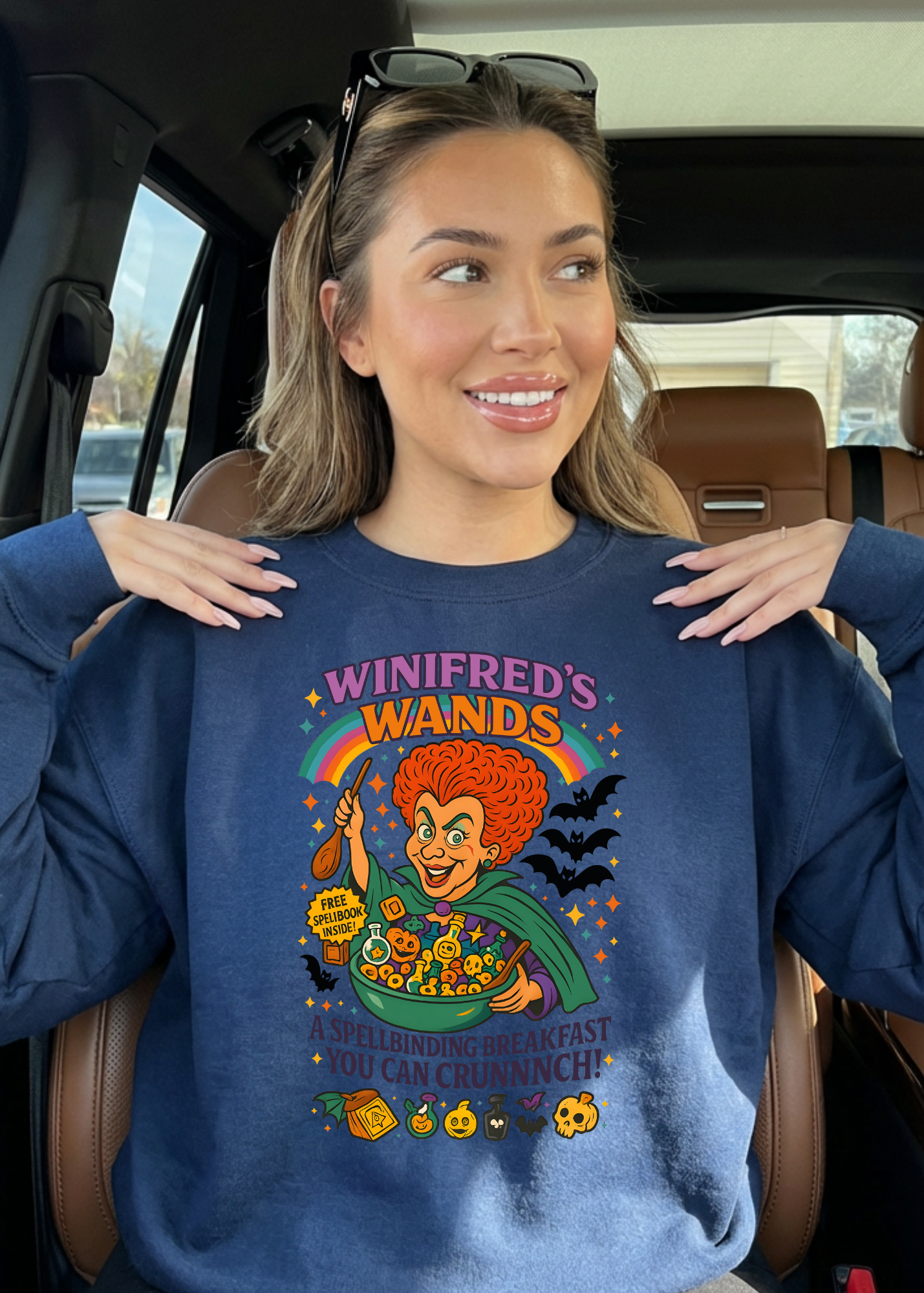Woman wearing a blue sweatshirt with a colorful graphic design inside a vehicle.