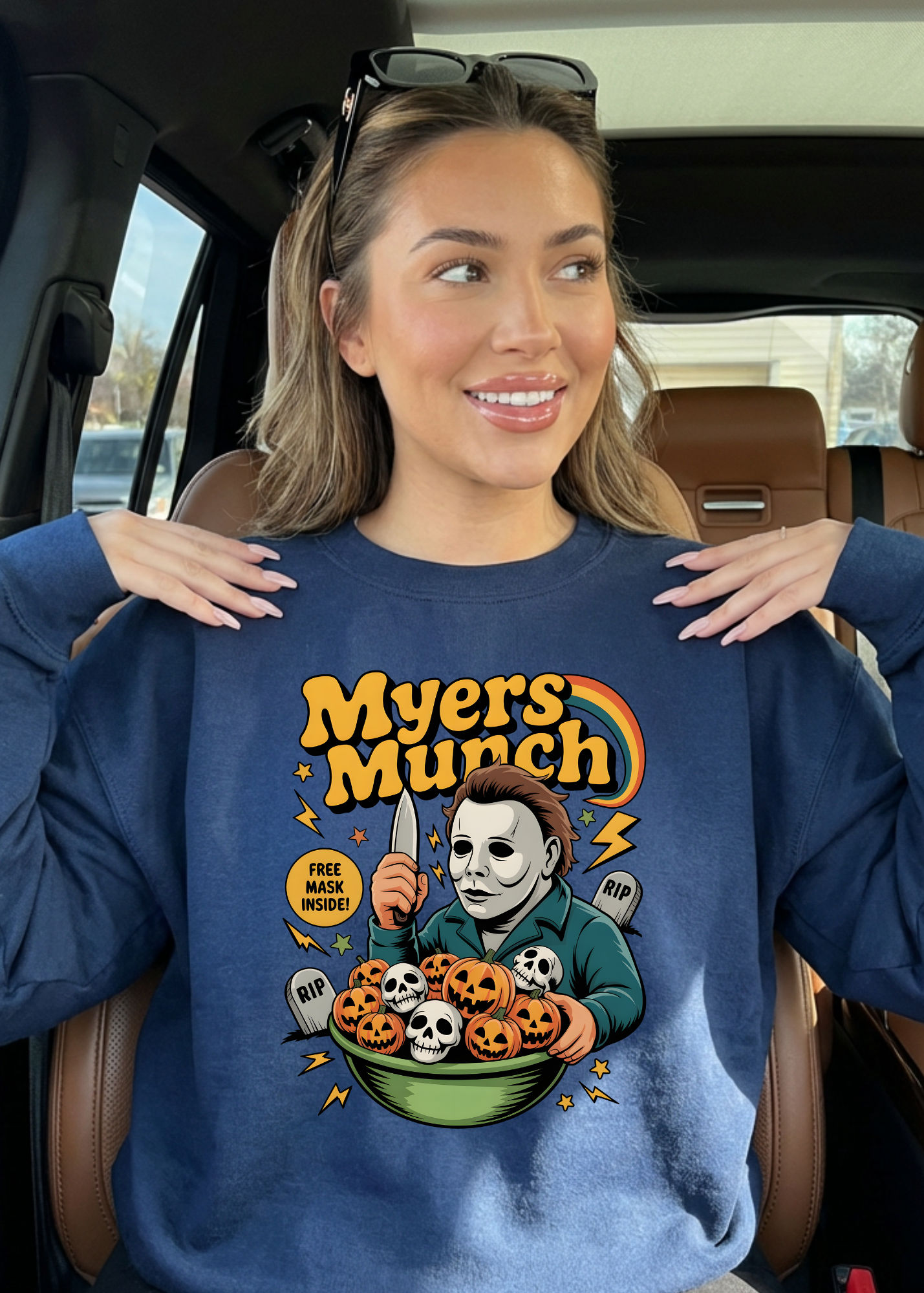 Woman wearing a blue sweatshirt with 'Myers Munch' graphic in a car.