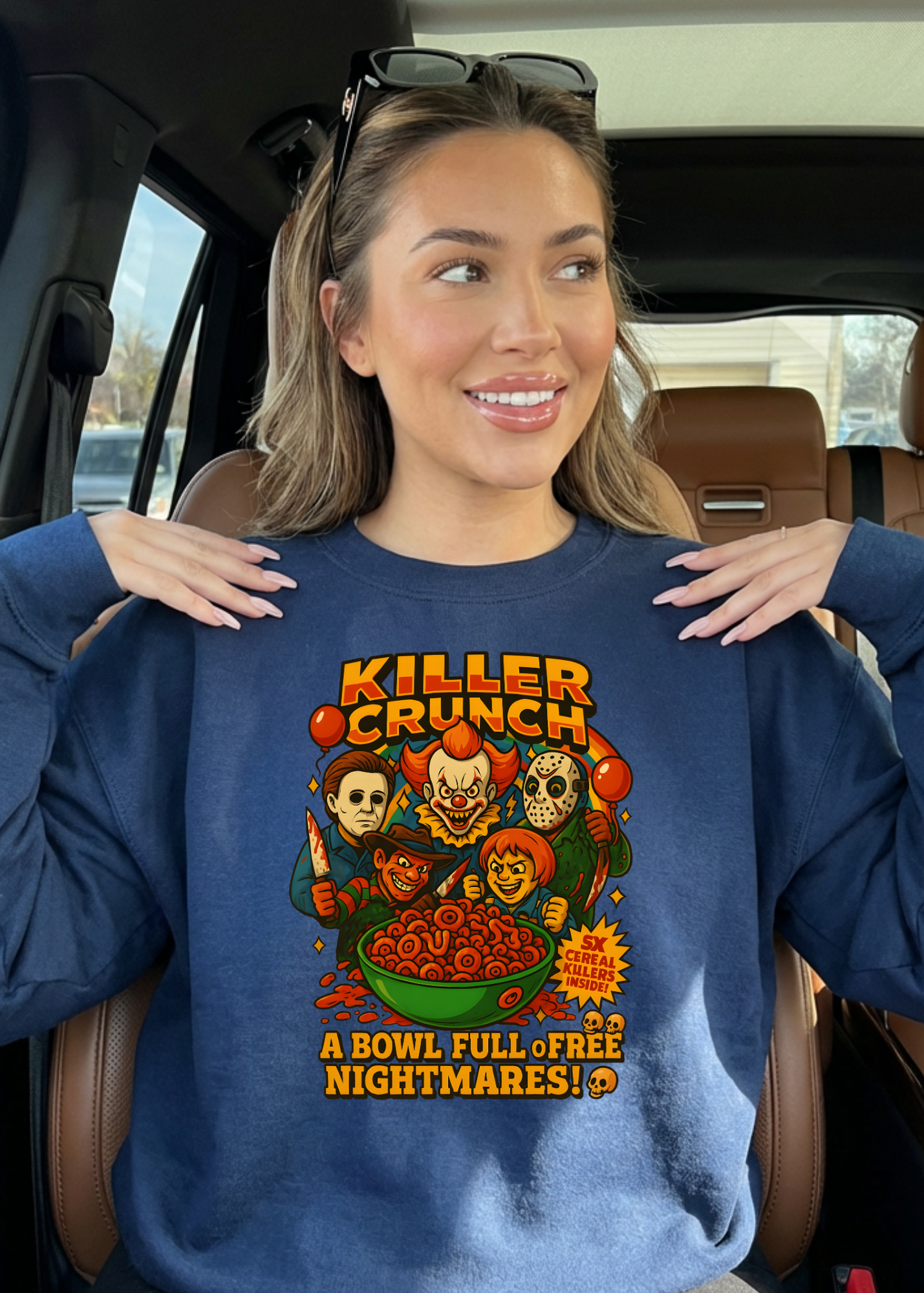 Woman wearing a blue sweatshirt with a graphic design inside a car