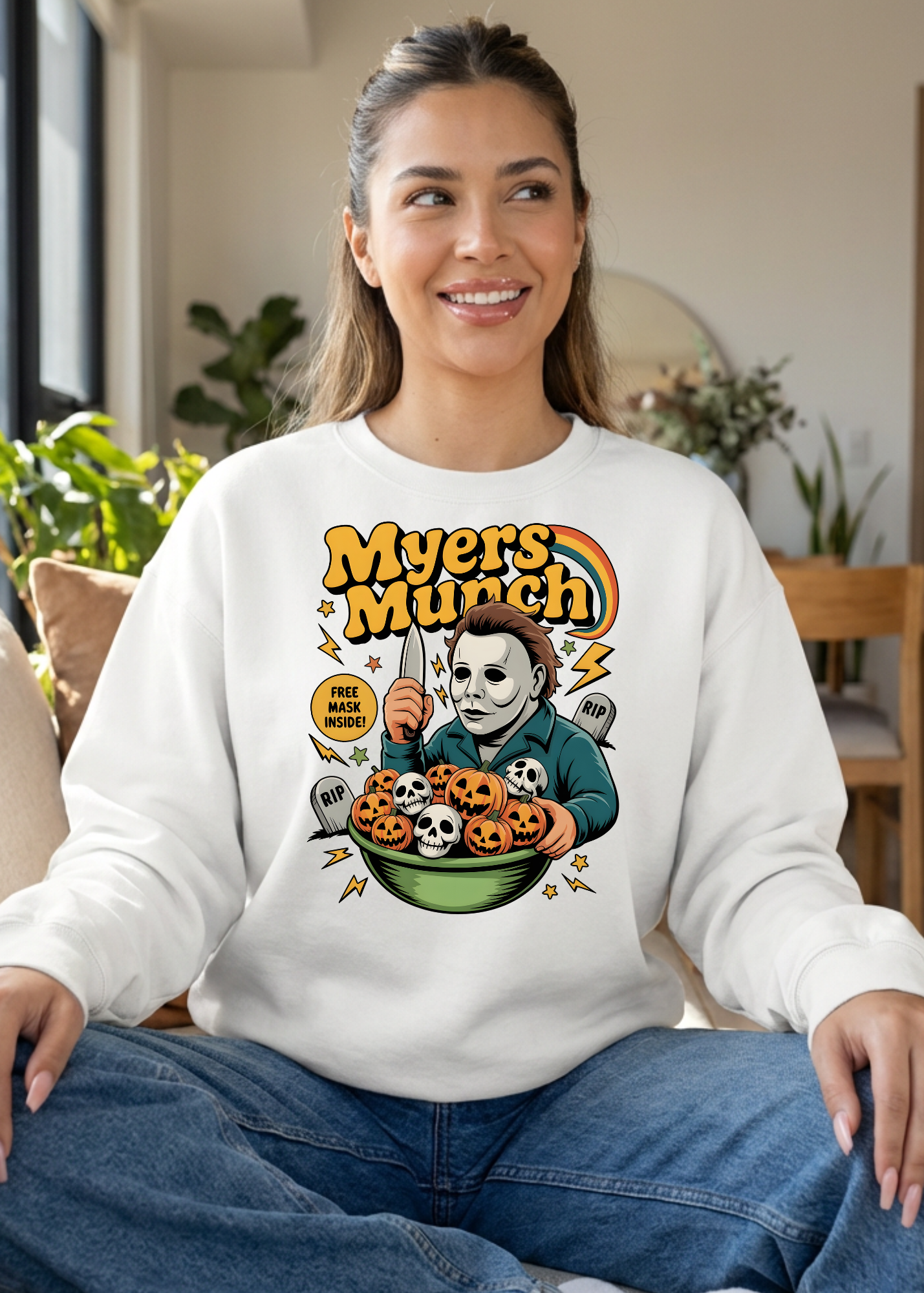 Woman wearing a white sweatshirt with a Halloween-themed graphic design sitting indoors.